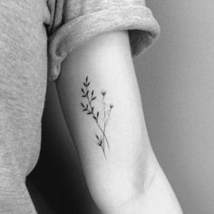 a black and white photo of a woman's arm with a flower tattoo on it