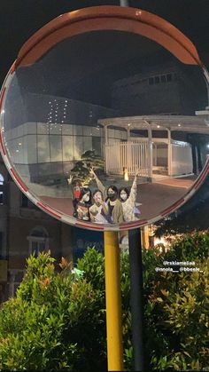 the reflection of people standing in front of a building is shown in a circular mirror