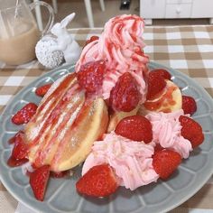 a plate topped with waffles covered in whipped cream and strawberries