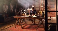 a man sitting at a desk in front of a lamp and books on the table