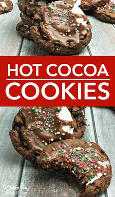 chocolate cookies with white and green sprinkles are on a wooden table next to a red sign that says hot cocoa cookies