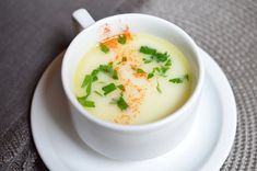 a white bowl filled with soup on top of a plate