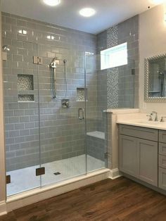 a bathroom with a walk in shower next to a white sink and wooden flooring