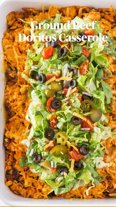 a white casserole dish filled with salad and olives, topped with shredded cheese