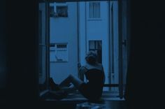 a woman sitting on a window sill in the dark