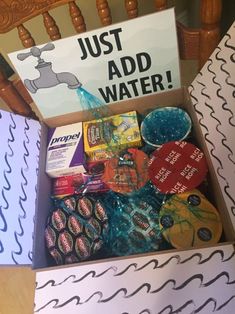 a box filled with assorted items sitting on top of a wooden chair next to a sign