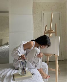 a woman is sitting on the floor in front of an easel