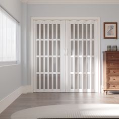 an empty room with two doors and a dresser in the corner on the far side