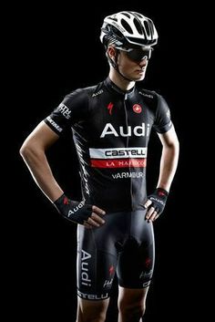 a man wearing a bike suit and helmet standing in front of a black background with his hands on his hips