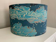 a lampshade with clouds and stars on it sitting on top of a dresser