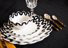 black and white dishes are arranged on a table with gold utensils in the foreground