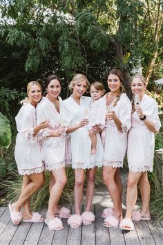 a group of women standing next to each other on a wooden floor covered in white robes