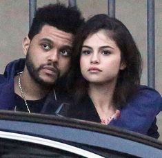 a man and woman standing next to each other in front of a building with bars