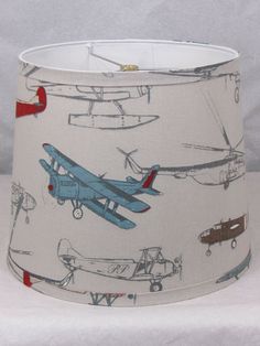 a lampshade with airplanes on it is sitting on a white tablecloth background