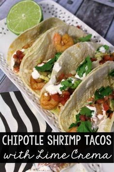 three shrimp tacos with lime and cilantro on a plate