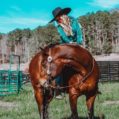 a woman wearing a cowboy hat riding on the back of a brown horse