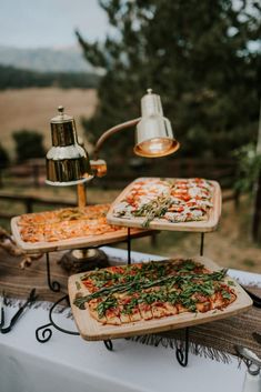 two pizzas on trays sitting on top of a table next to a lamp