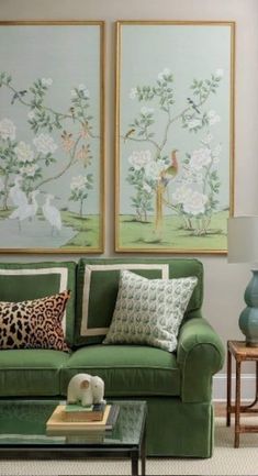 a living room with green couches and paintings on the wall above them, along with coffee table