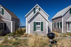 three small gray houses with green shutters on the front and one in the back