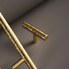 two gold cufflinks on a gray surface, one has a long bar in the middle