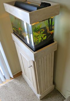 a fish tank sitting on top of a wooden cabinet next to a wall and door