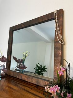 a large mirror sitting on top of a wooden shelf next to flowers and vases