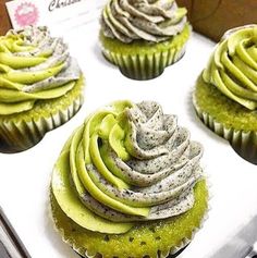 four cupcakes with green frosting in a box