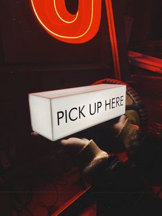 there is a sign that says pick up here in front of a red neon light