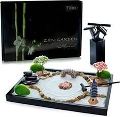 a black tray with flowers and rocks on it next to an open box that says zen garden