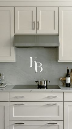 a kitchen with white cabinets and stainless steel appliances, including a wine bottle on the counter