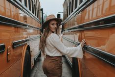 a woman standing in front of a bus with her hands on the door and looking at the camera