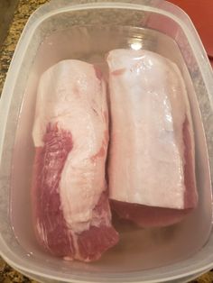 two pieces of raw meat in a plastic container