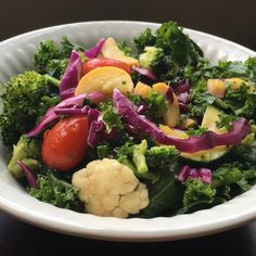 a white bowl filled with vegetables on top of a wooden table