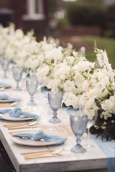 the table is set with white flowers and blue napkins