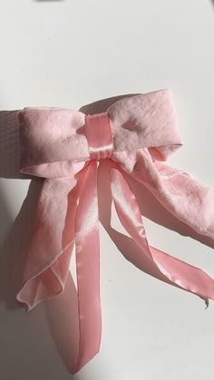 a pink ribbon tied to the side of a white wall with an object in the background