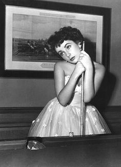 a black and white photo of a woman in a short dress holding a baseball bat