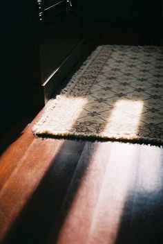 the sun is shining on an area rug that has been placed on top of a wooden floor