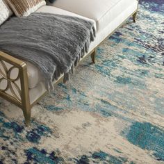 a large blue and white area rug in a living room with a couch, ottoman and pillows