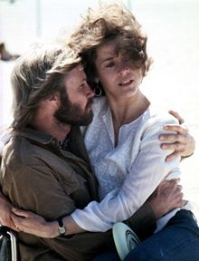 a man and woman embracing each other on the beach