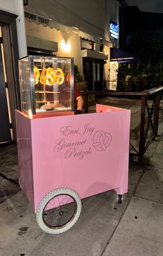 a pink cart sitting on the side of a street next to a sidewalk with lights