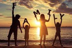 a family standing on the beach with their arms in the air and letters spelling out