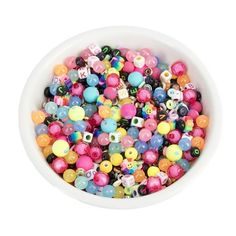 a white bowl filled with lots of colorful beads