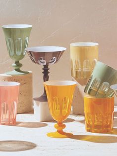 there are many different colored glass cups on the table and one is upside down,