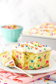 a slice of cake with white frosting and sprinkles on a plate