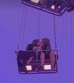 two people sitting on a ferris wheel kissing