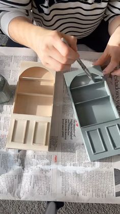 a woman is painting the inside of a doll house with paint and paper on it