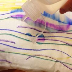 someone is using a plastic bottle to spray paint on a t - shirt with colorful lines