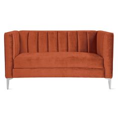 an orange velvet sofa with metal legs on a white background in front of a plain backdrop