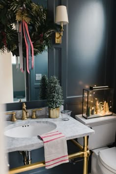 a bathroom decorated for christmas with wreath, toilet and sink