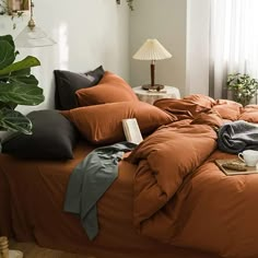 an unmade bed with orange sheets and pillows